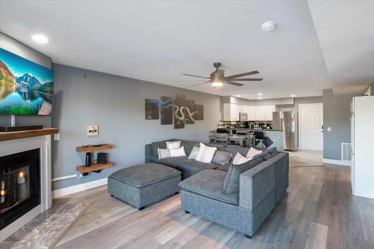 A spacious, comfortable living area with a cozy sofa, fireplace, television, and a view of the adjoining kitchen. Artwork and decor create a welcoming ambiance, ideal for unwinding after a night exploring Osage Beach. The space encourages guests to relax, share stories, or enjoy a movie together.