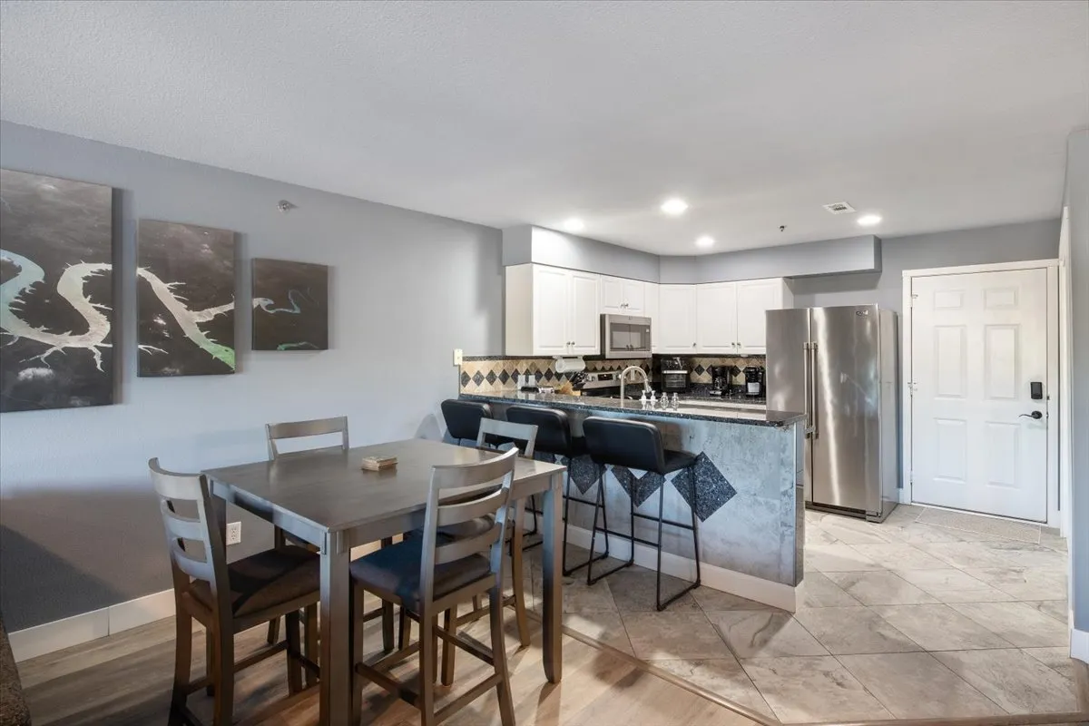 A cozy dining area adjacent to the kitchen, featuring a dining table, a kitchen island, and bright, contemporary artwork on the wall. The setting is intimate and inviting, ideal for both everyday dining and special gatherings.