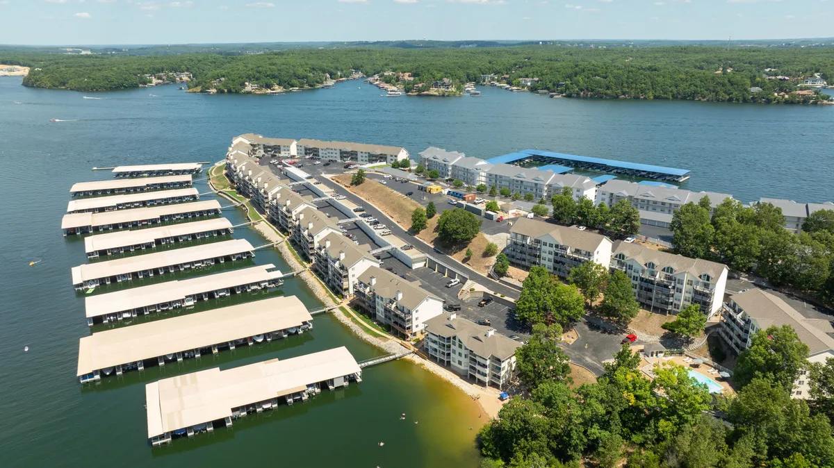 An expansive view of the marina and waterfront, where condominium buildings and boat slips line the shore. Green spaces and calm water evoke a leisurely mood, suggesting opportunities for boating, waterfront strolls, or simply appreciating the scenic environment.