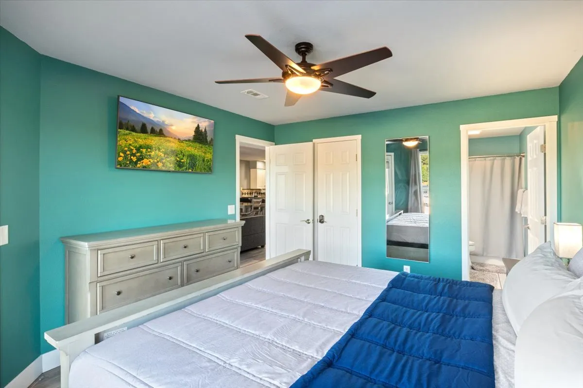 A bright, calm bedroom furnished with a bed, dresser, wall art, and mirror. The setup exudes a peaceful and uncluttered ambiance, ideal for private relaxation and restorative sleep.
