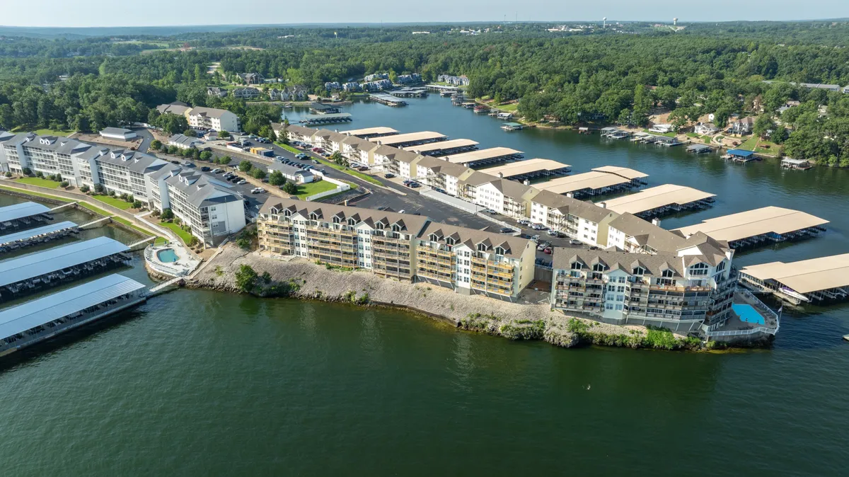 The community’s exterior features waterfront views with boat docks and residential buildings lining the shore. The ambiance is peaceful yet social, ideal for relaxed gatherings by the water or launching an evening adventure into Osage Beach’s vibrant scene.
