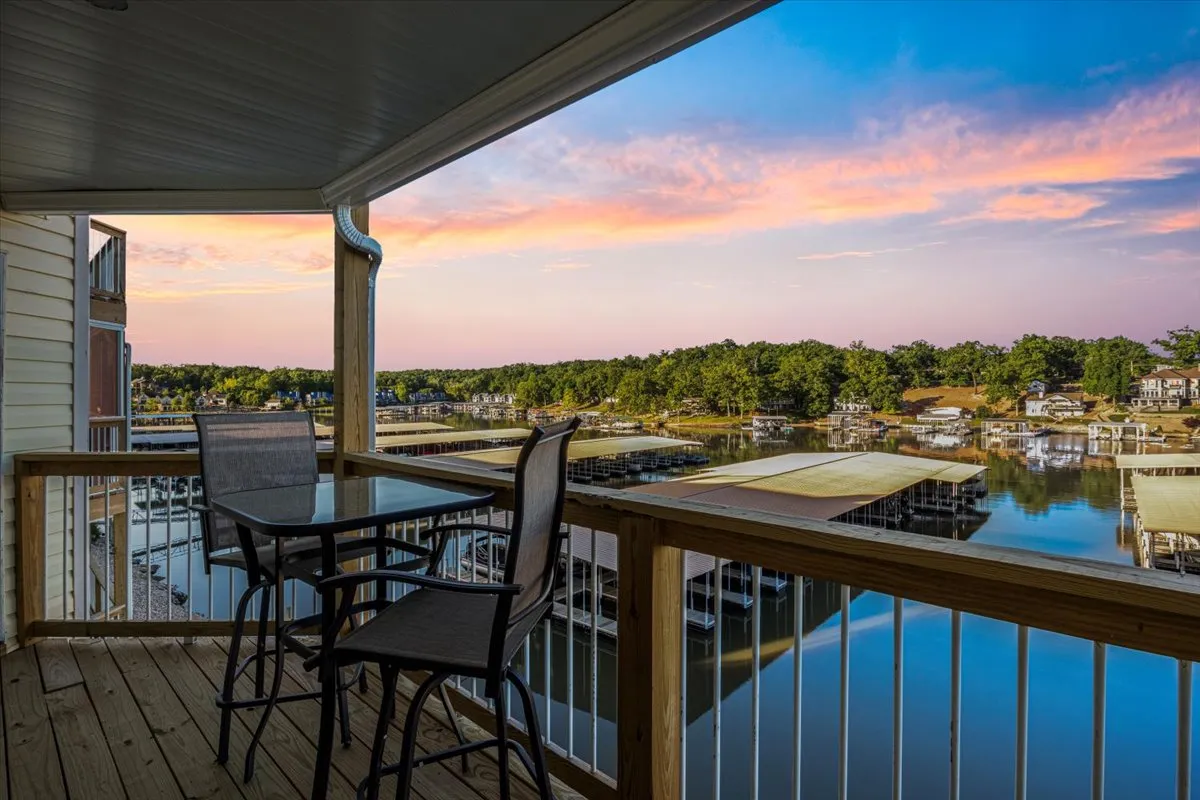 A serene balcony scene with comfortable seating overlooking the lake and a colorful sunset sky. The balcony offers a private retreat to relax with a drink, watch boats drift by, or simply enjoy the beauty of dusk over the water.